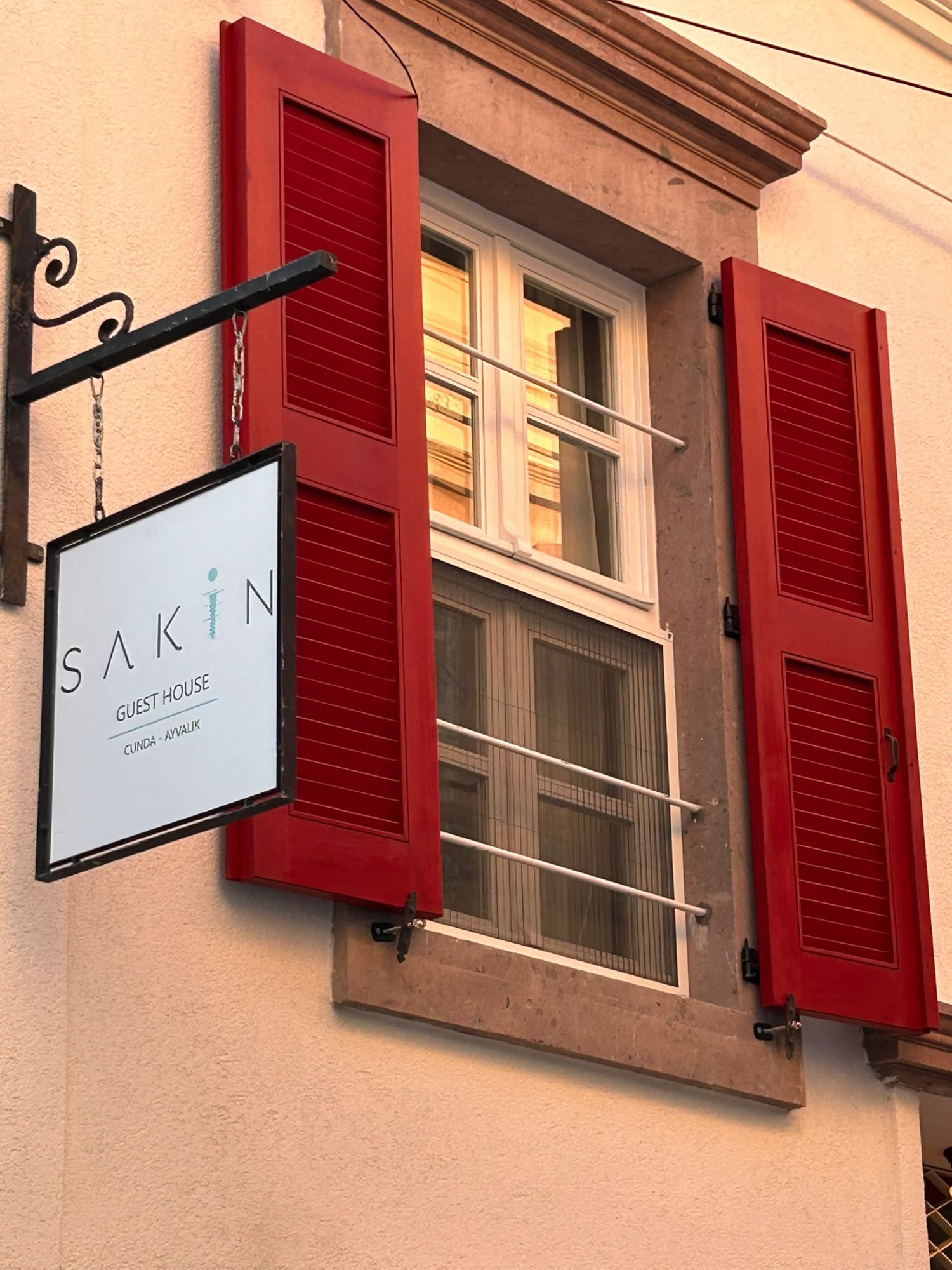 Sakin Guest House tabelası ve kırmızı panjurlar, Cunda